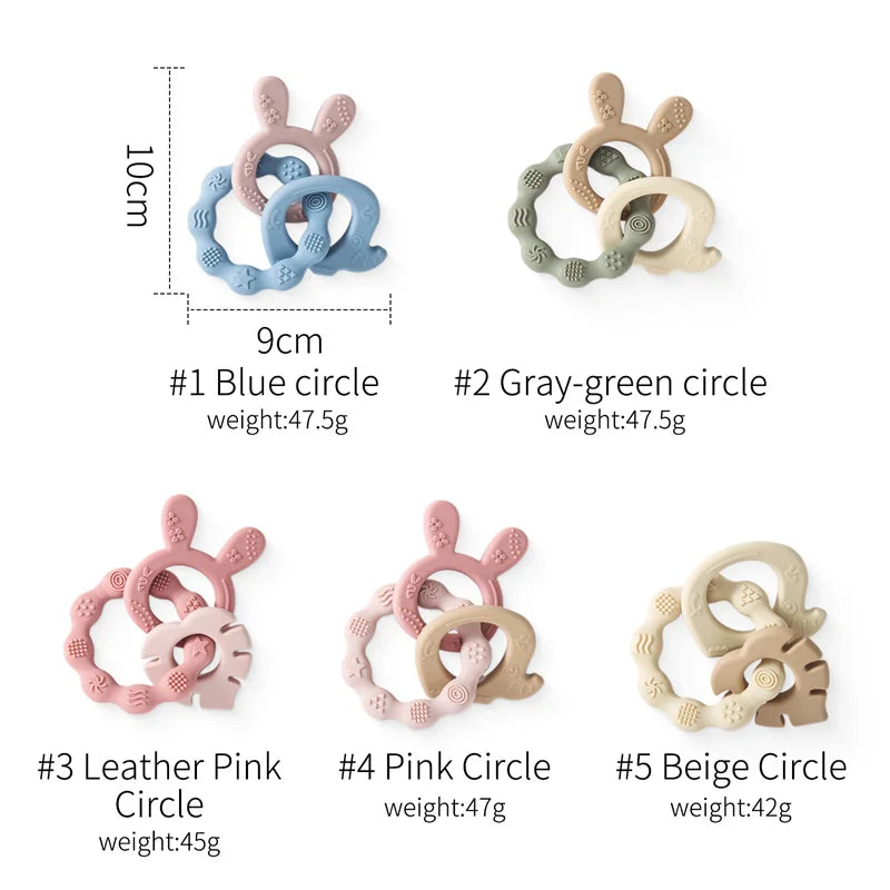 Silicone rabbit ear baby teethers in blue, gray-green, pink, and beige, with textured rings.