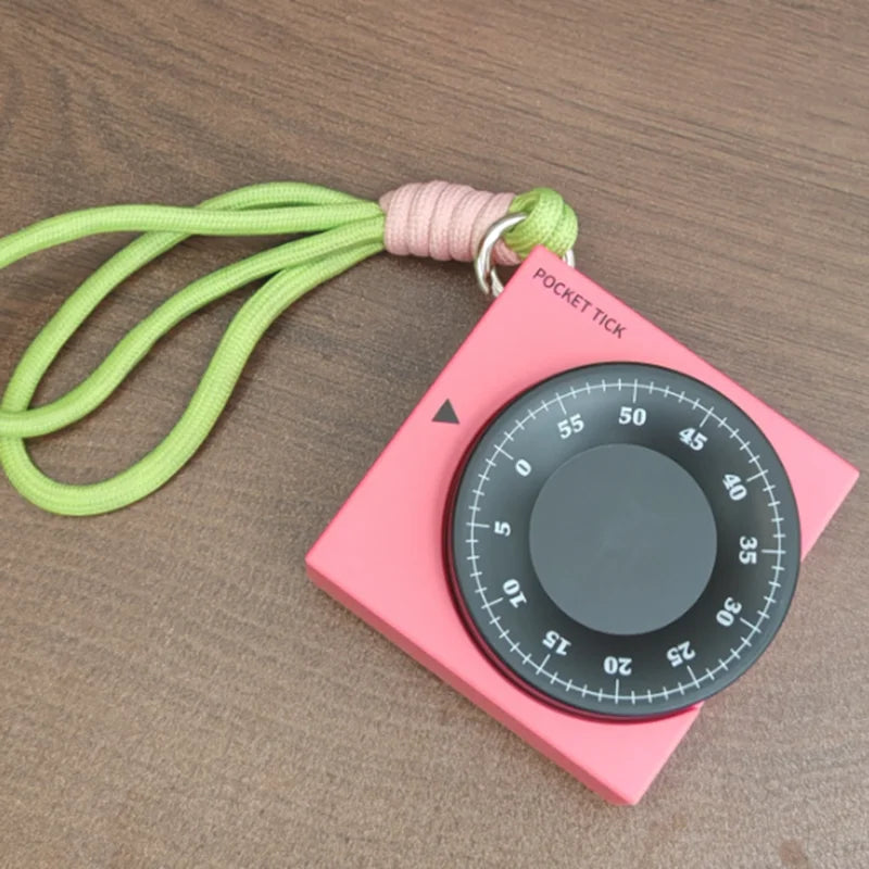Pink square visual timer with a black 60-minute dial, "POCKET TICK" text, and a green lanyard.