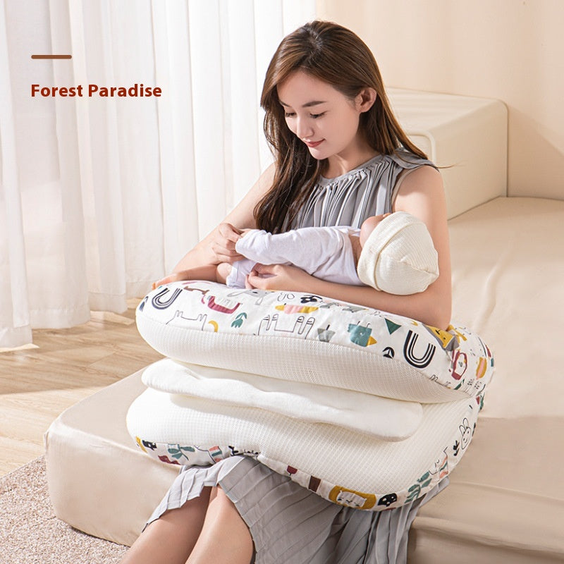 Smiling mother cradling baby on a white, patterned multi-use nursing pillow.