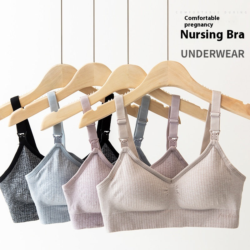Wireless ribbed nursing bras in black, blue, purple, and beige, hanging on wooden hangers.