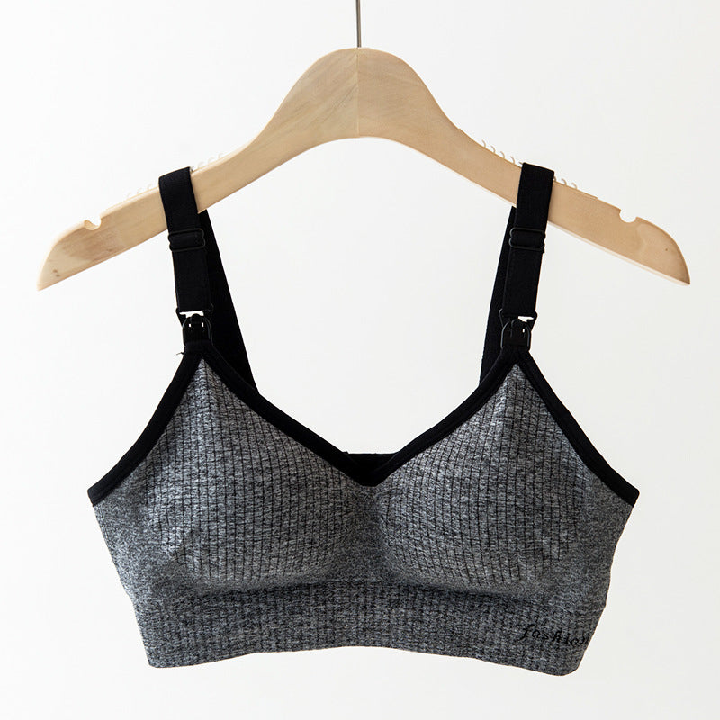 Gray ribbed wireless nursing bra with black trim and adjustable straps, hanging on a wooden hanger.
