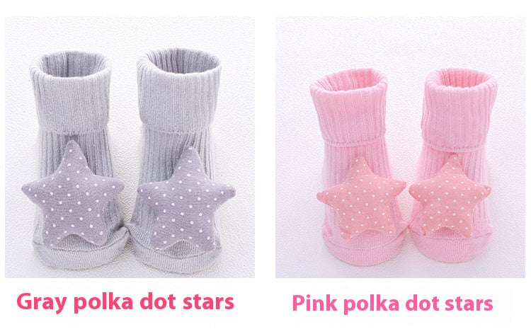 Two pairs of baby cotton socks with anti-slip soles, one gray with polka dot stars, one pink with polka dot stars.