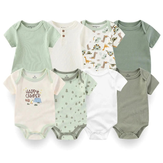 Eight short-sleeve cotton baby bodysuits in white, sage green, and cream with dinosaur, tree, and "Happy Camper" prints.