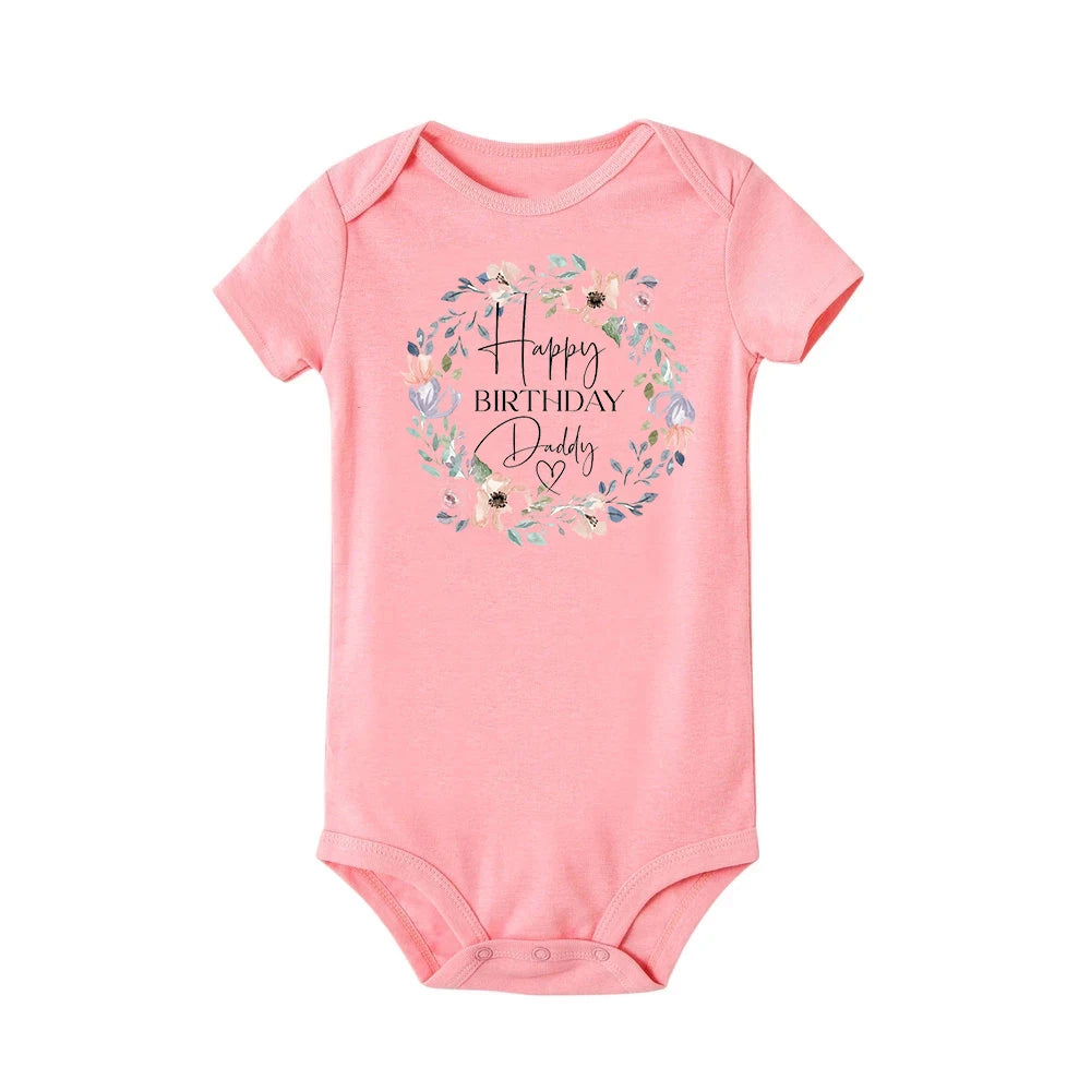 Pink short-sleeve baby bodysuit with "Happy Birthday Daddy" in a floral wreath design.