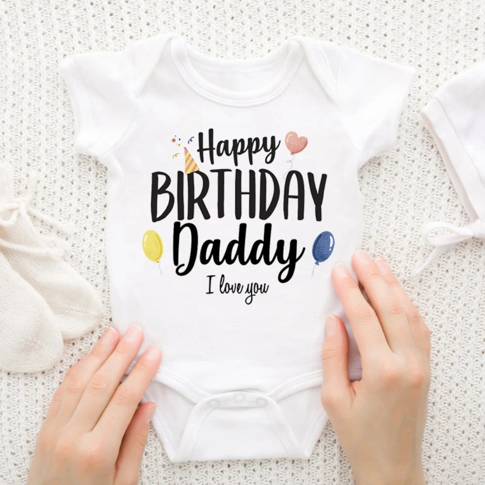 White baby bodysuit with "Happy Birthday Daddy I love you" text, party hat, balloons, and hearts.