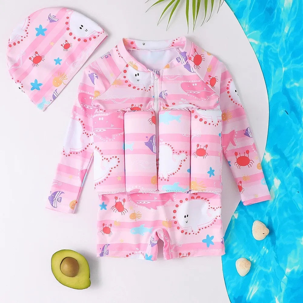 Pink long-sleeve kids' floatation swimsuit with cartoon crabs, fish, and stars, includes a matching swim cap.