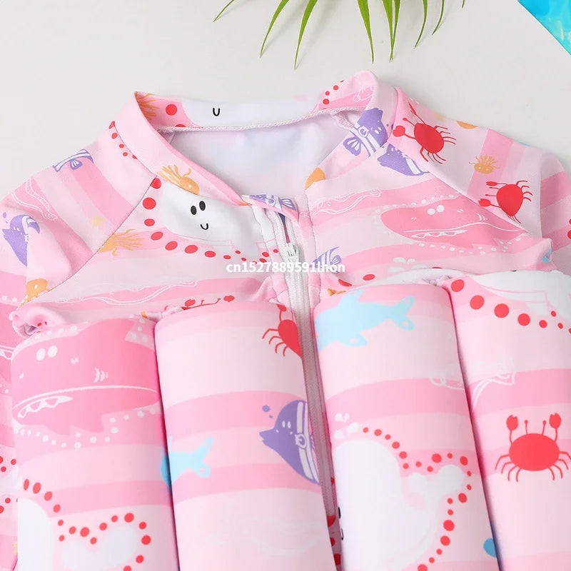 Pink children's floatation swimsuit with colorful cartoon crabs, fish, and stripes, featuring a front zipper.