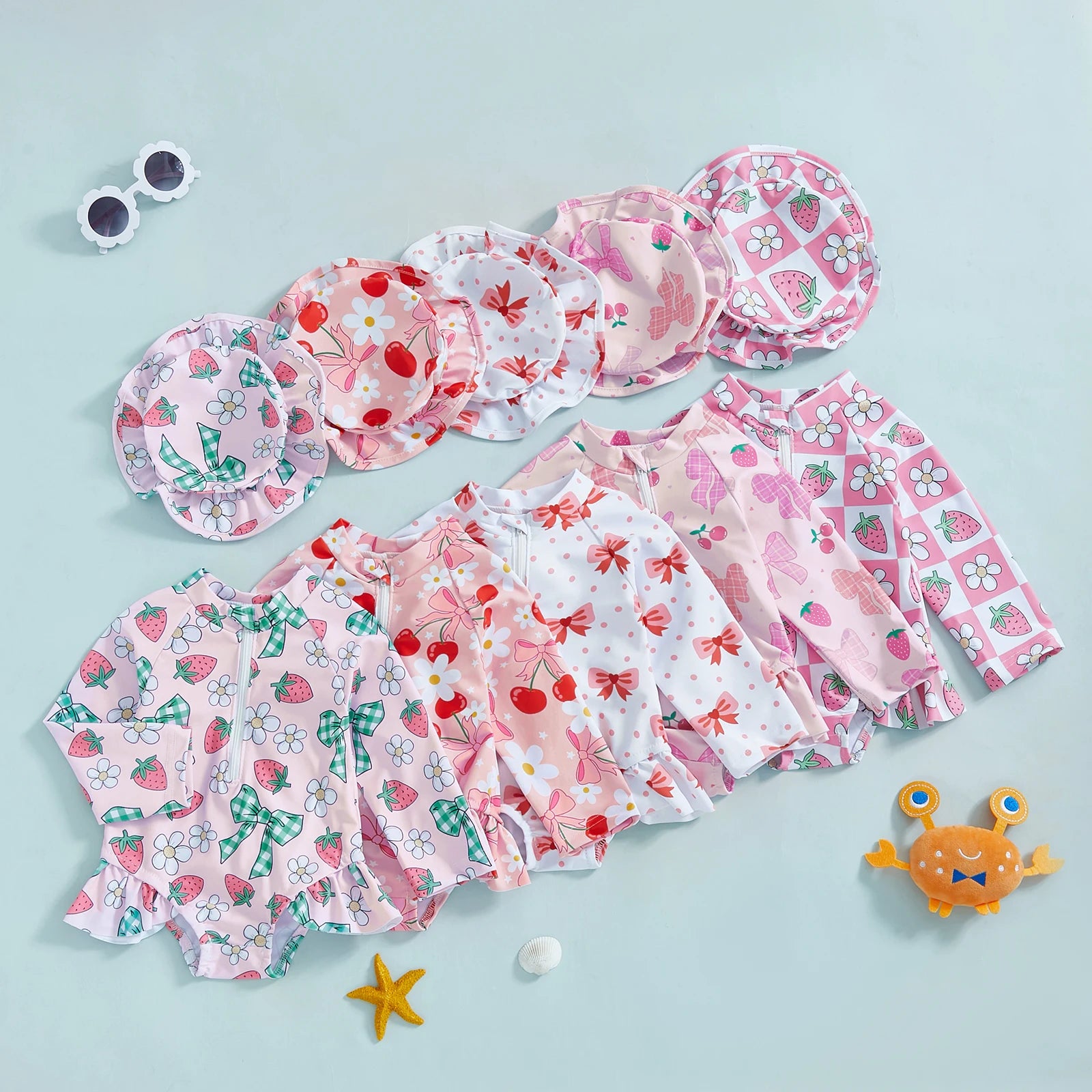 Infant long-sleeve rashguard swimsuits with matching hats in various pink floral and fruit prints.