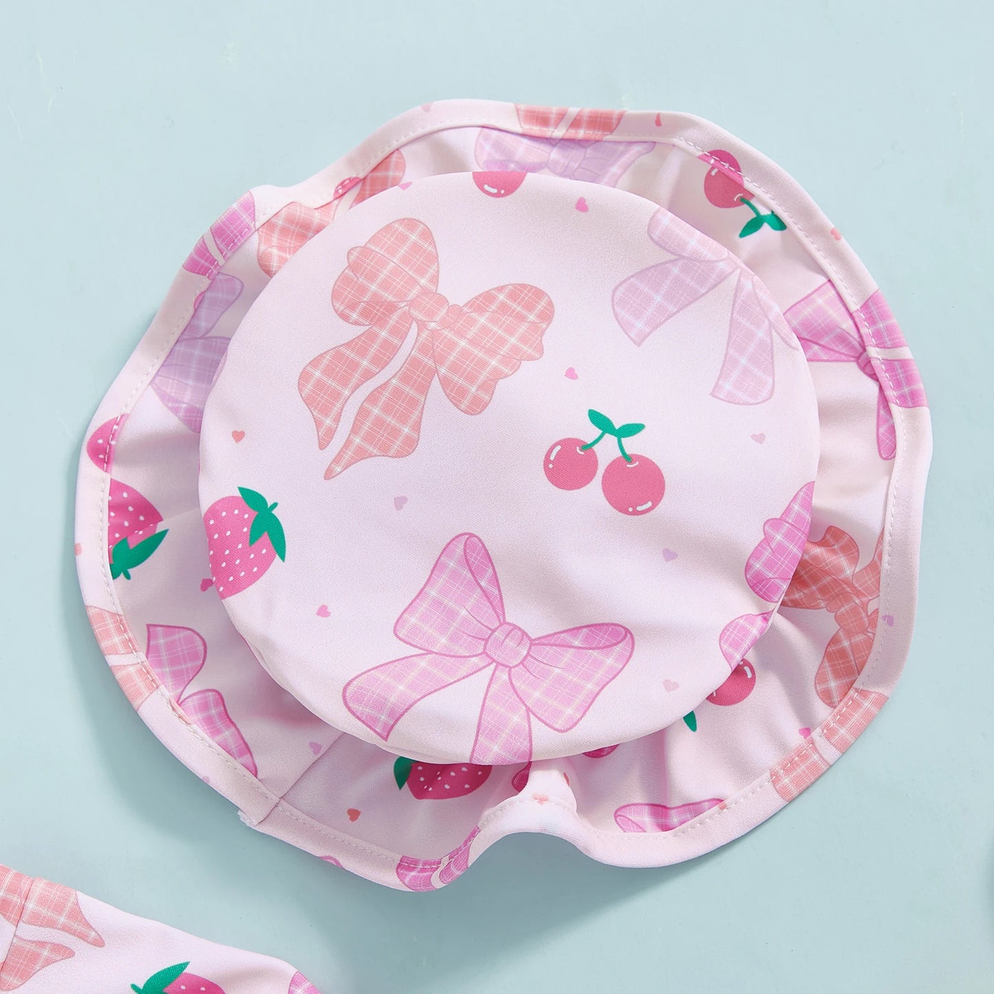 Pink floral rashguard swimsuit set for babies, featuring bows, strawberries, and cherries, with a matching sun hat.