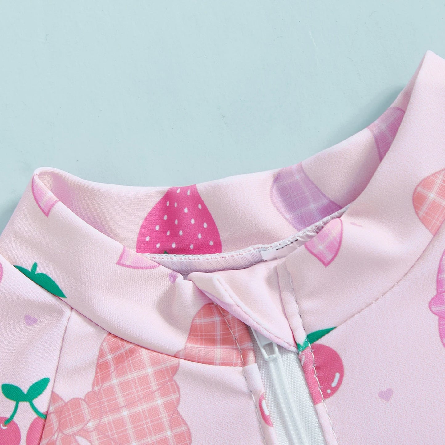 Pink long-sleeve rashguard swimsuit for babies, featuring a floral/fruit pattern and a white front zipper.