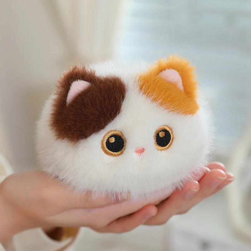 Soft, fluffy white, brown, and orange calico cat plush toy held in hands.