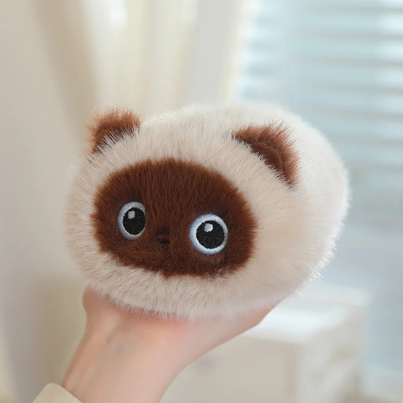 Soft, fluffy cream and brown round cat plush toy held in a hand.