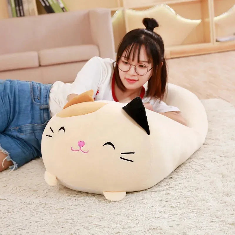 Soft plush cartoon cat pillow in cream, black, and pink, held by a woman on a rug.