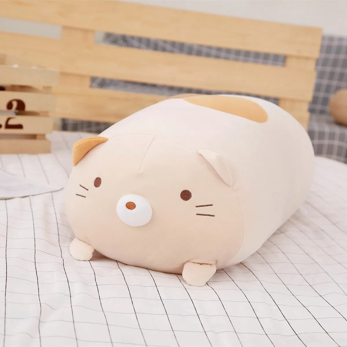 Soft beige plush cat pillow with brown spots and embroidered face.