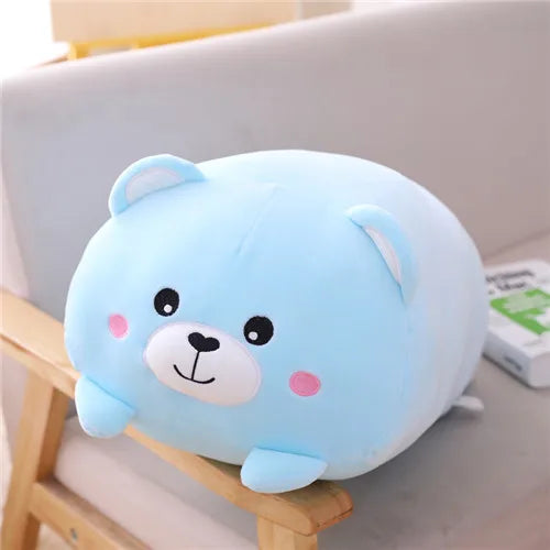 Soft blue plush bear toy with pink cheeks, black eyes, and a small smile, resting on a chair.