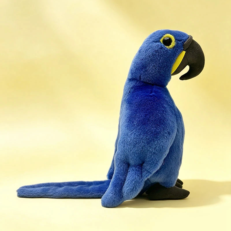 Soft, plush 22cm blue parrot toy with black beak and yellow eye details, standing on a yellow background.