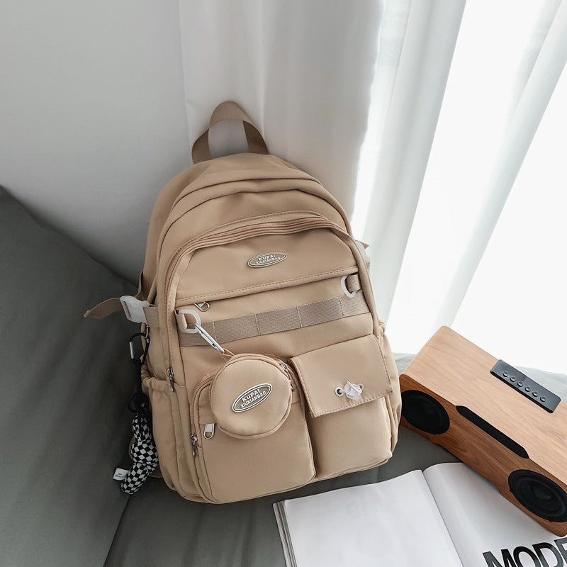 Beige nylon student backpack with laptop compartment, multiple pockets, and a matching coin pouch.