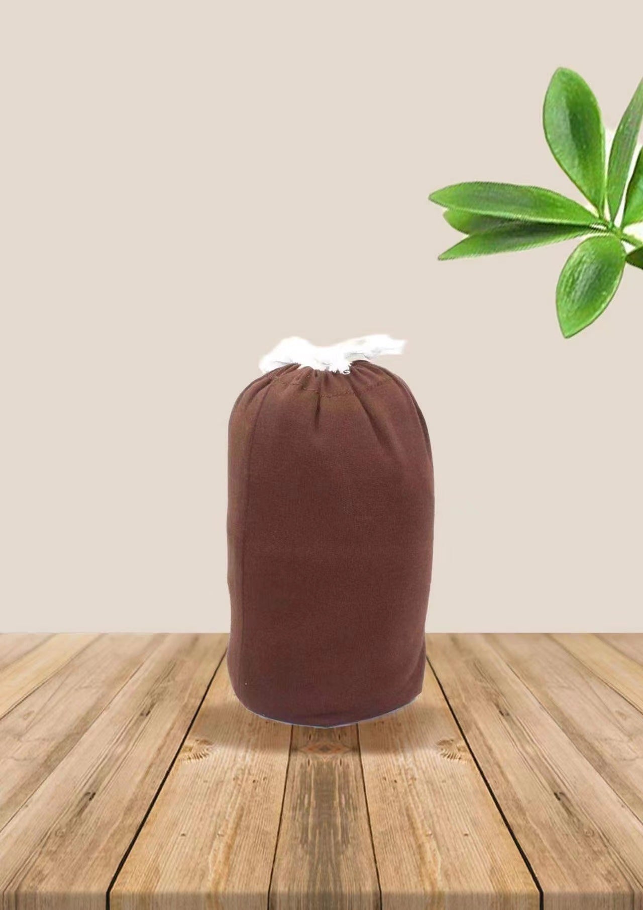 Brown soft ergonomic baby wrap carrier, folded and tied with white string, on a wooden surface.