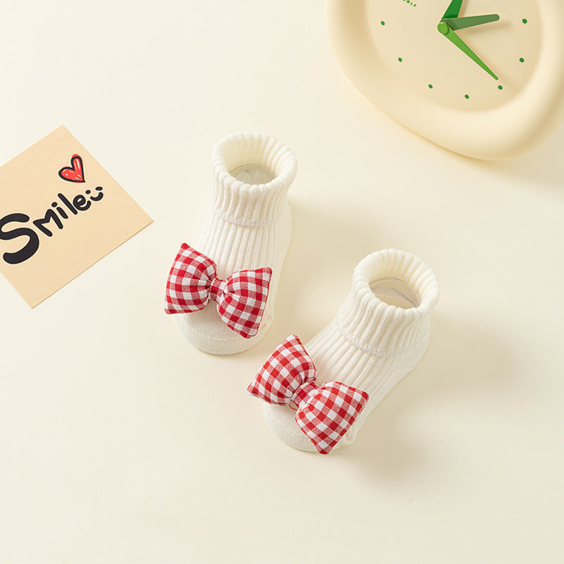 White ribbed cotton baby socks with red and white checkered bows and anti-slip soles.