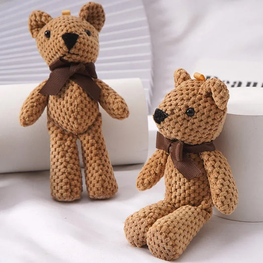 Two small, brown crocheted teddy bears with dark brown bows, one standing and one sitting.