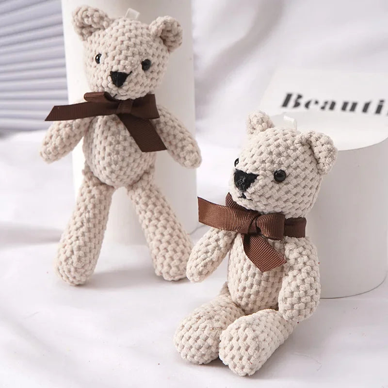 Two small, beige knitted teddy bears with brown bows, one standing and one sitting.