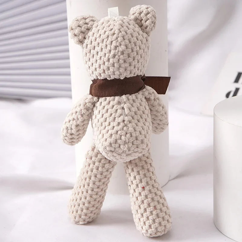 Soft beige plush teddy bear, 16cm, with textured knit and brown ribbon scarf.