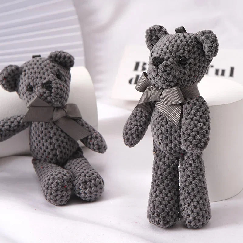 Two small, dark gray knitted teddy bears with matching bows, one sitting and one standing.