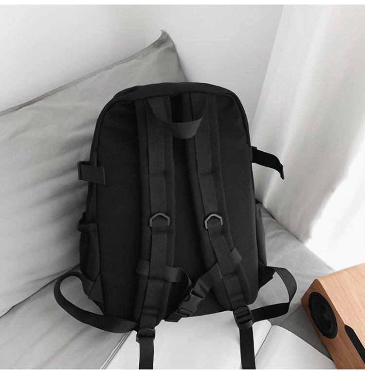 Black nylon student backpack with padded ergonomic shoulder straps and side buckles.