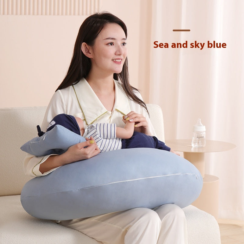 Smiling mother holding a baby on a light blue, ergonomic nursing pillow.