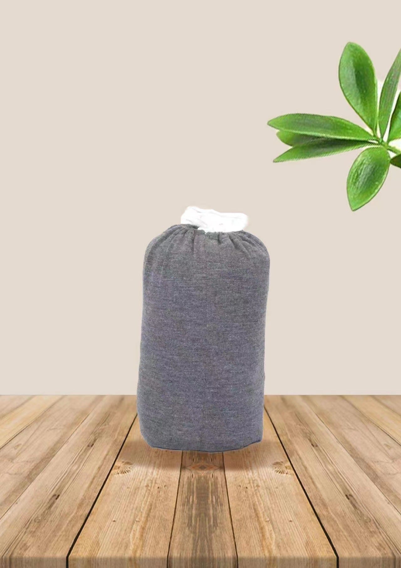 Gray soft ergonomic baby wrap carrier, folded, with a white top, on a wooden surface.