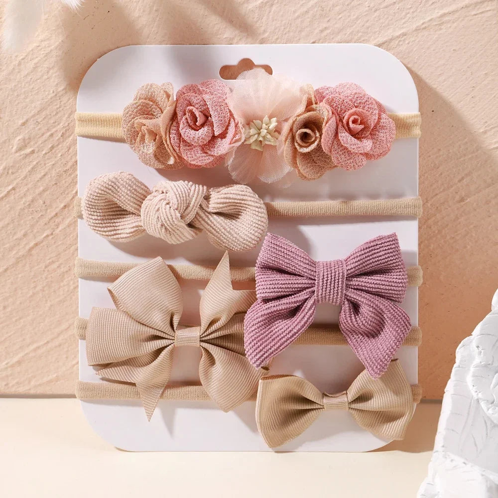 Set of 5 baby headbands with pink lace flowers, ribbed bows, and plain beige bows.