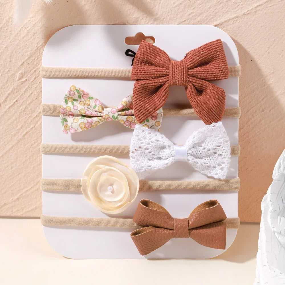Set of 5 baby headbands: rust corduroy bow, floral bow, white lace bow, cream flower, and brown faux leather bow.