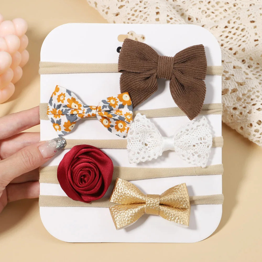 Set of 5 baby headbands: brown corduroy bow, floral bow, white lace bow, red rose, and gold faux leather bow.