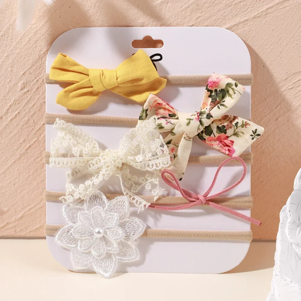Set of 5 baby headbands: yellow bow, floral bow, lace bow, pink string bow, and white lace flower with pearl.