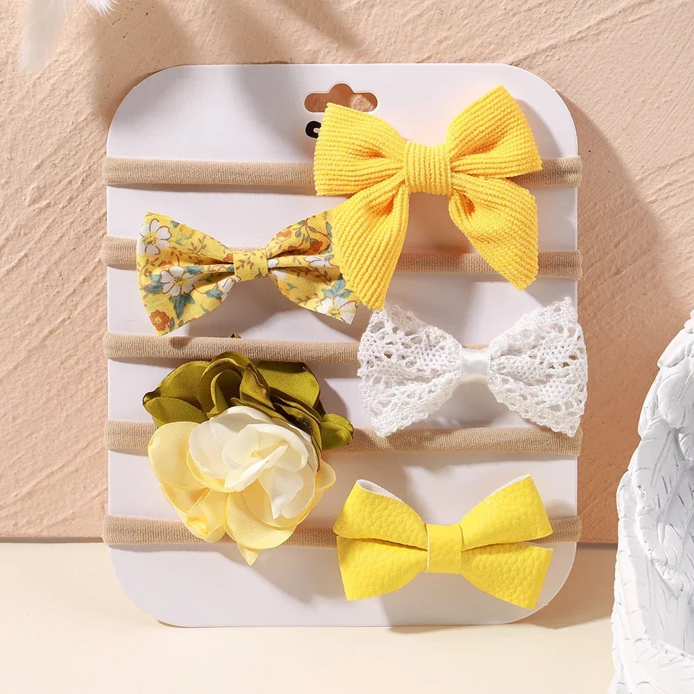 Set of 5 baby headbands with yellow bows, floral print, and white lace designs on soft nylon.
