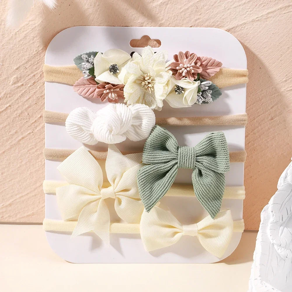 Set of 5 baby headbands: floral, lace, and bow designs in cream, beige, and sage green.