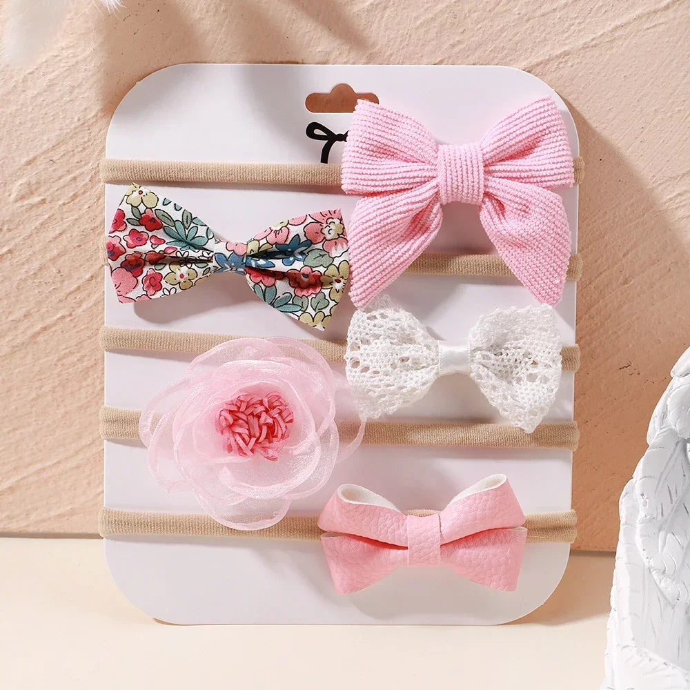 Set of 5 baby headbands: pink ribbed bow, floral bow, white lace bow, pink organza flower, and pink faux leather bow.