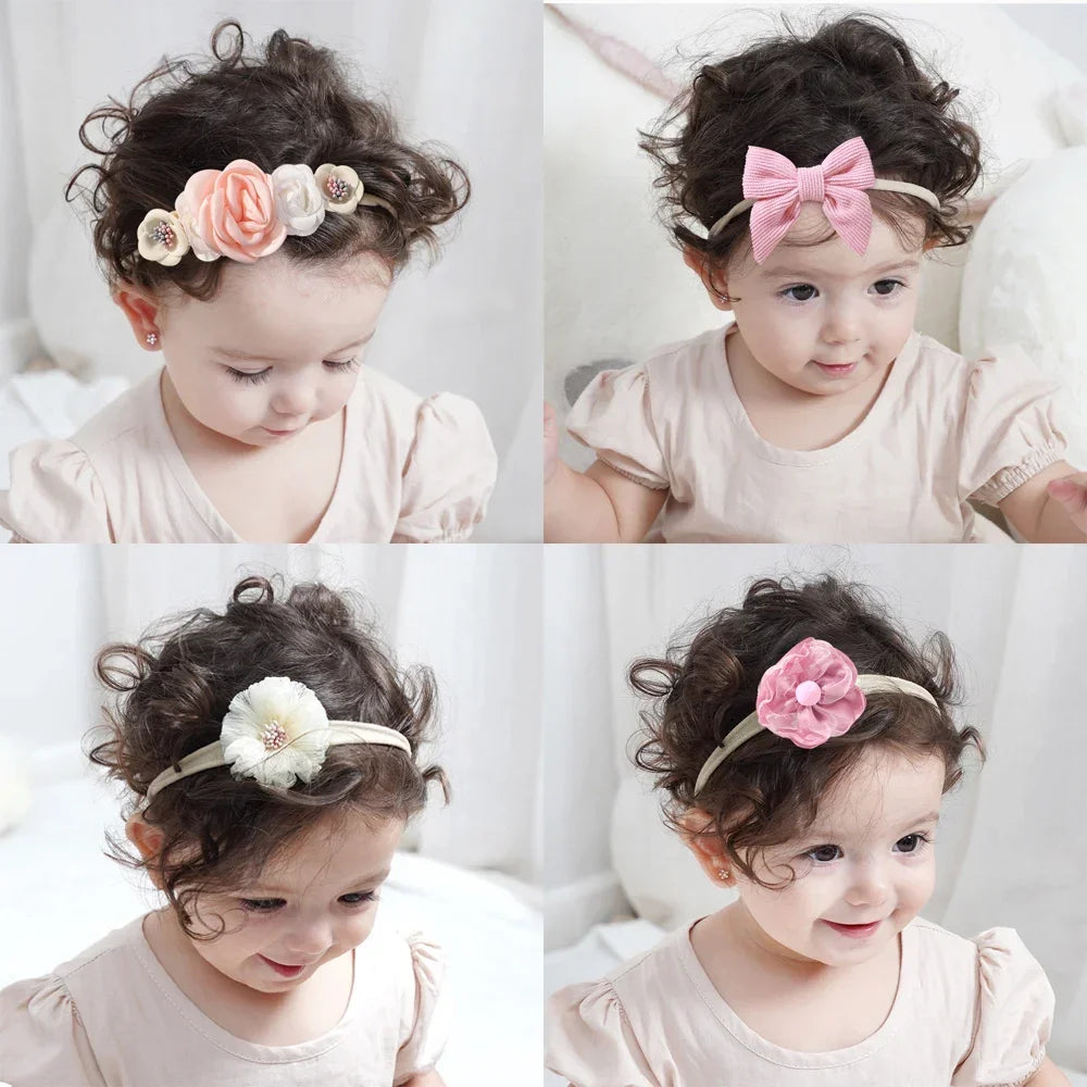 Set of 5 baby headbands with lace flowers and bows in pink, peach, and white, worn by a baby.