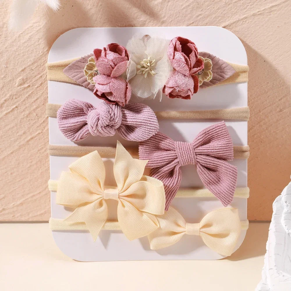 Set of 5 baby headbands with pink lace flowers, ribbed bows, and cream satin bows.