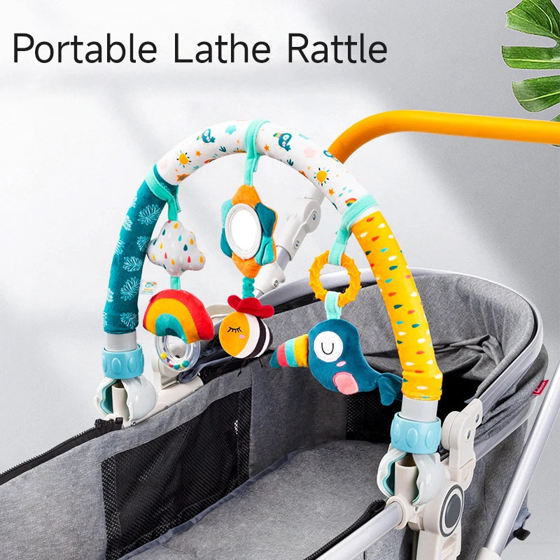 Adjustable baby activity arch with colorful plush rattles, mirror, and bird toy, attached to a gray bassinet.