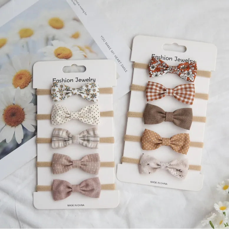 Two sets of handmade baby headbands with bow ties in various floral, polka dot, and plaid patterns.