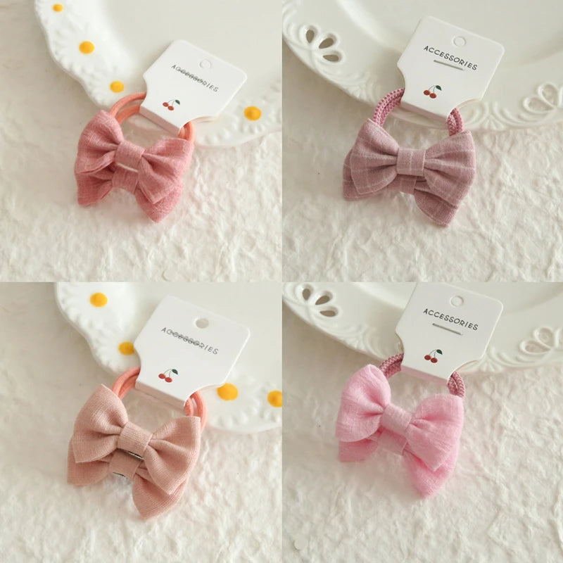 Four pink cotton hair bows on soft elastic bands for babies and girls, displayed on white plates.