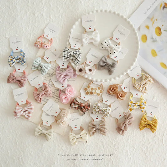 Assortment of soft cotton hair bows and elastic ties for babies and girls in various colors and patterns.