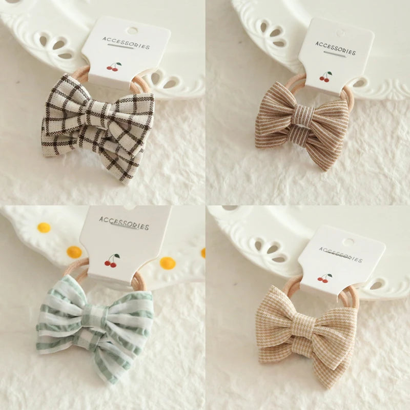Four cotton hair ties for babies and girls, featuring bows in plaid, striped, and solid patterns.