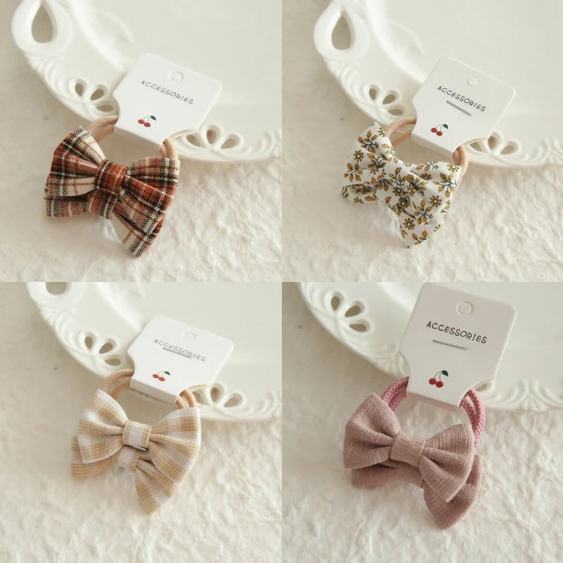 Four soft cotton hair ties for babies and girls, featuring plaid, floral, and solid pink bow designs.