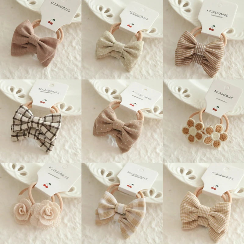 Assorted beige and brown cotton hair bows and floral elastic ties for babies and girls.