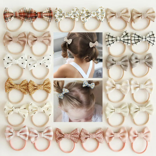 Assorted baby headbands and hair clips with various bow designs in plaid, floral, polka dot, and solid colors.