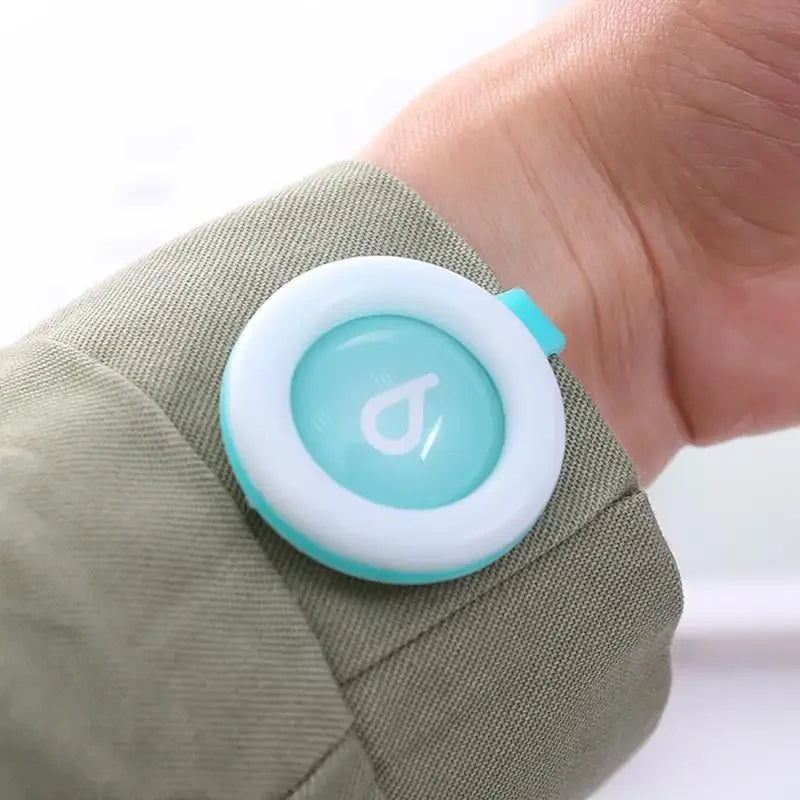 Round white and teal natural mosquito repellent clip attached to a sleeve, with a drop icon.