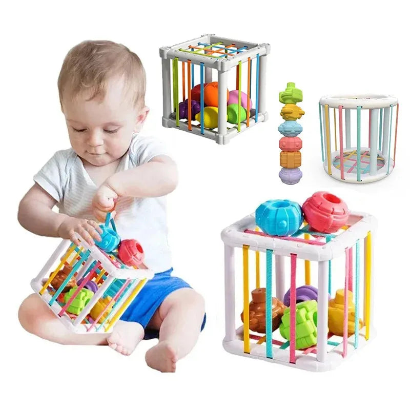 Baby playing with a white Montessori sorting cube featuring colorful elastic bands and various shaped blocks.