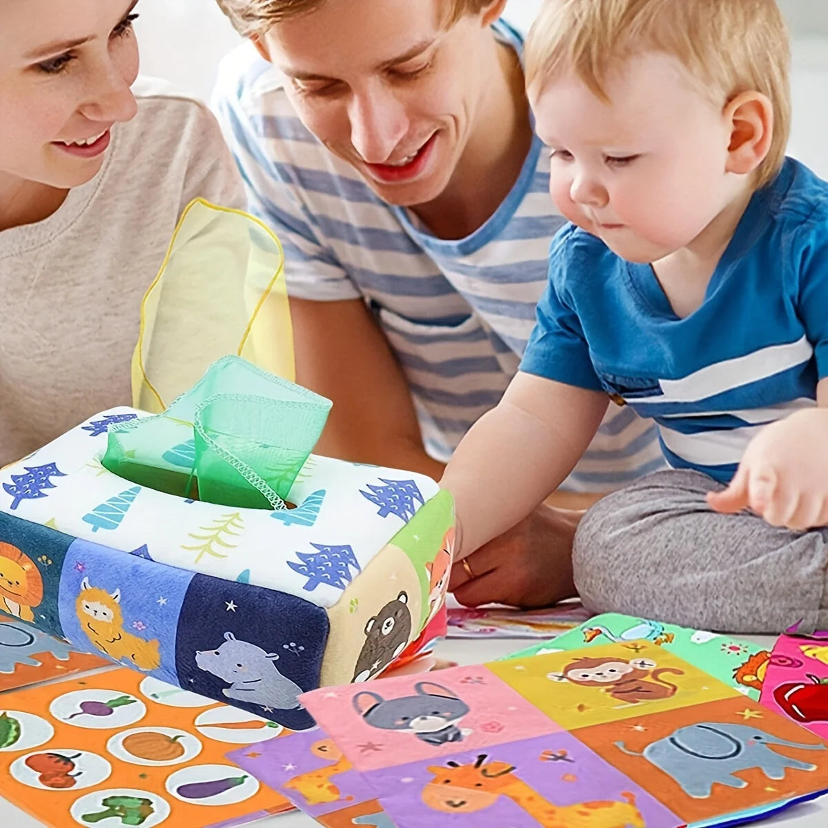 Soft fabric Montessori tissue box toy with colorful animal and nature patterns, surrounded by a family.